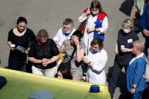 Medics and friends help a woman board an ambulance at a school after a shooting in Kazan, Russi ...