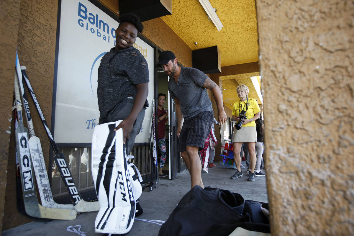 Former Golden Knights player Deryk Engelland, right, helps goalie Davon Duncan, 12, left, befor ...