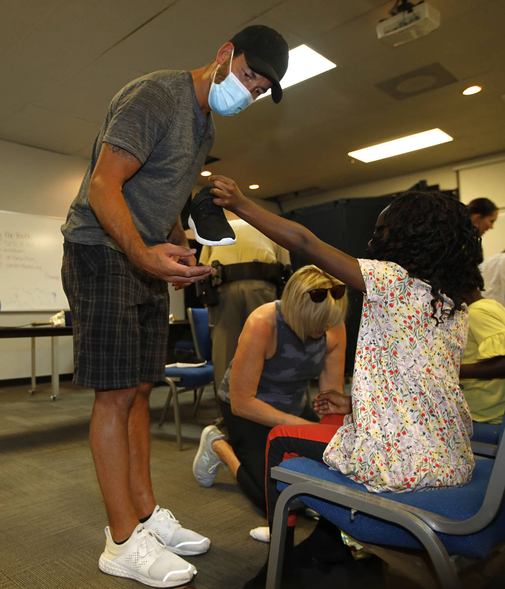 Former Golden Knights player Deryk Engelland help Skylrn Prevail, 7, to fit news shoes at Balm ...