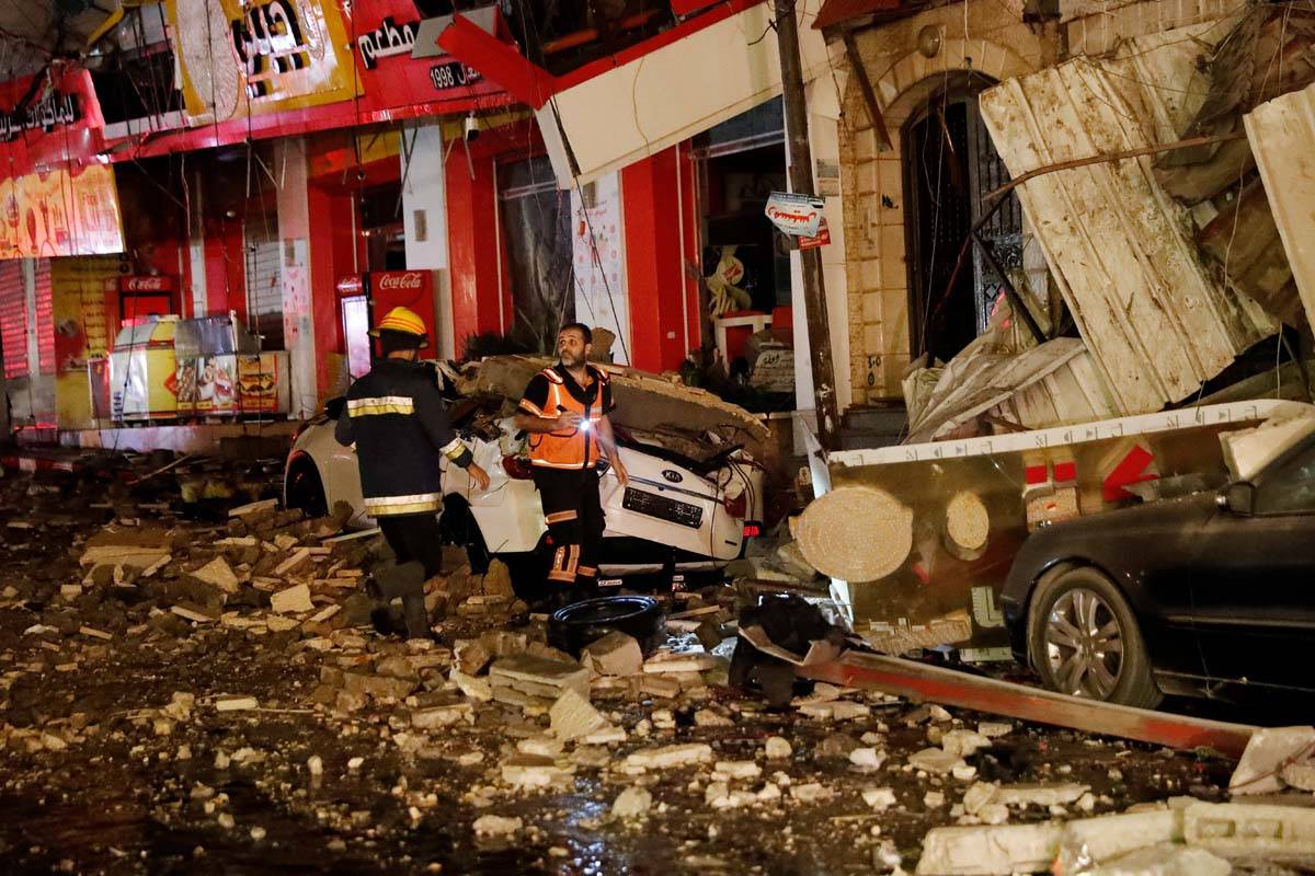 Firefighters inspect destroyed buildings after it was hit by Israeli airstrikes, in Gaza City, ...