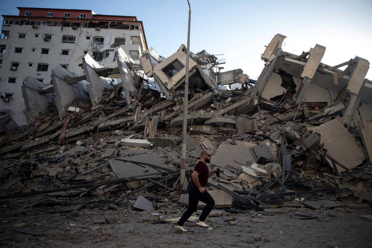 A Palestinian man passes by the remains of a building destroyed by Israeli airstrikes on Gaza C ...