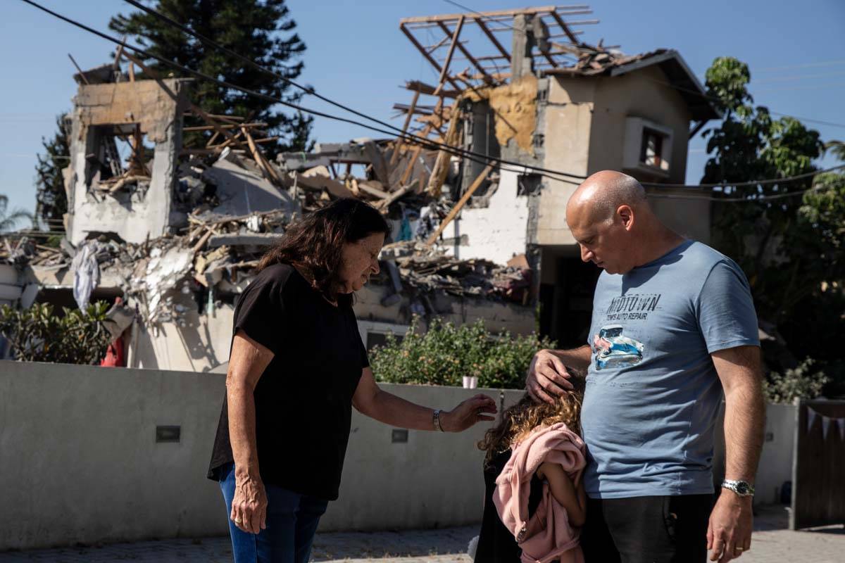 A young girl is comforted by her father next to a house damaged by a rocket fired from the Gaza ...