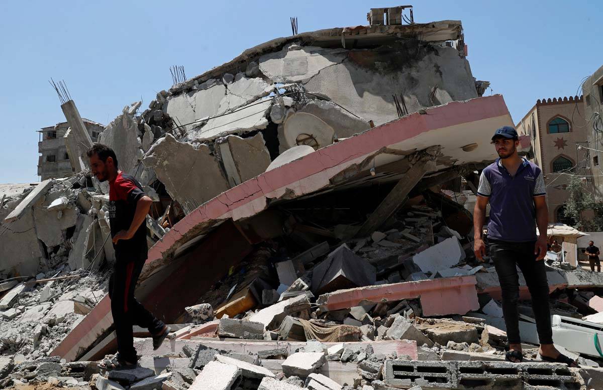 People walk amid the rubble of a destroyed residential building which was hit by Israeli airstr ...