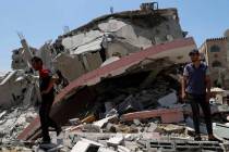 People walk amid the rubble of a destroyed residential building which was hit by Israeli airstr ...