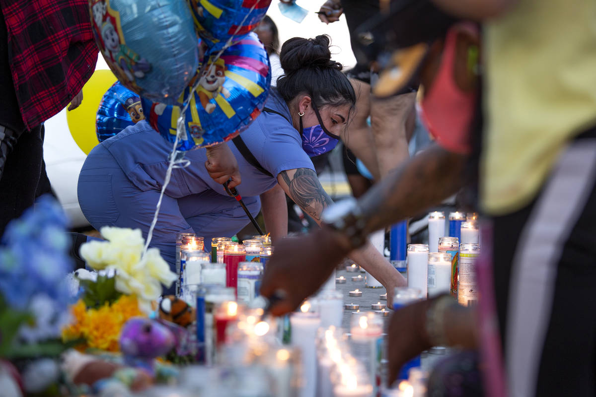 Angel Calderon, center, lights candle during a vigil for 2-year-old Amari Nicholson outside the ...