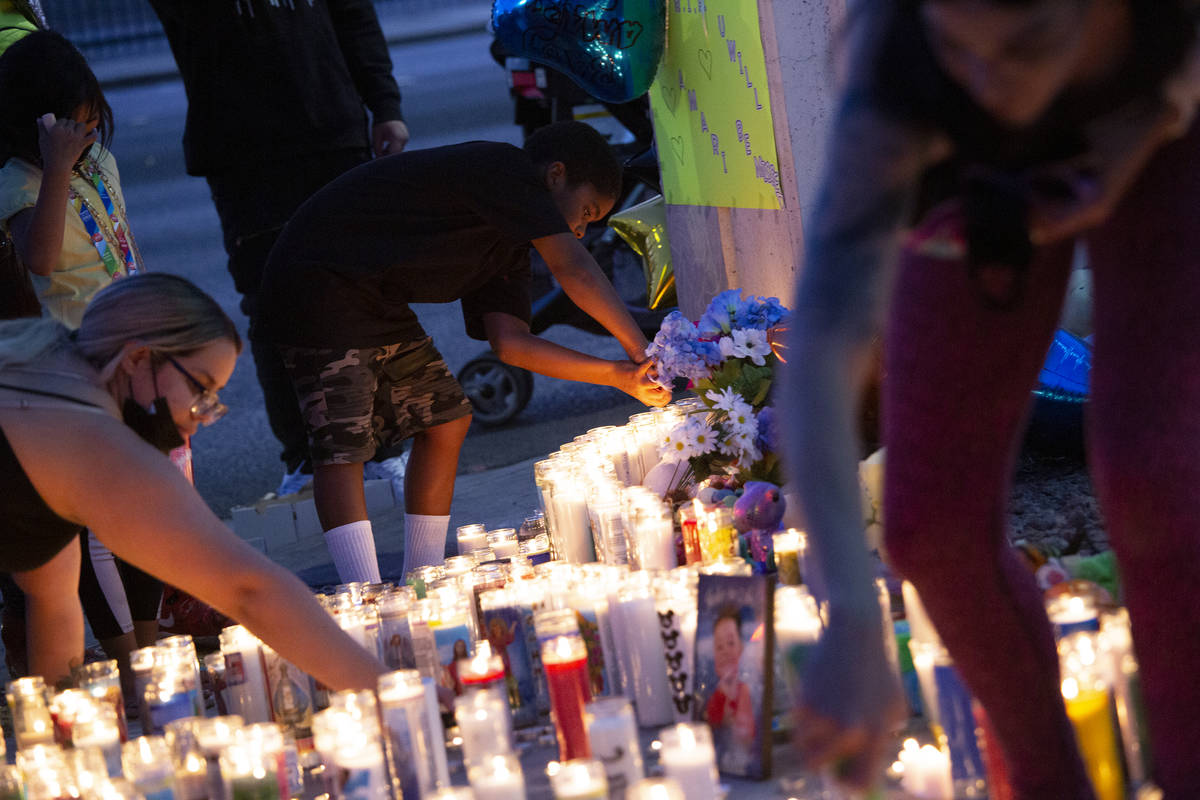As the wind blows out the candles, mourners keep them lit during a vigil for 2-year-old Amari N ...