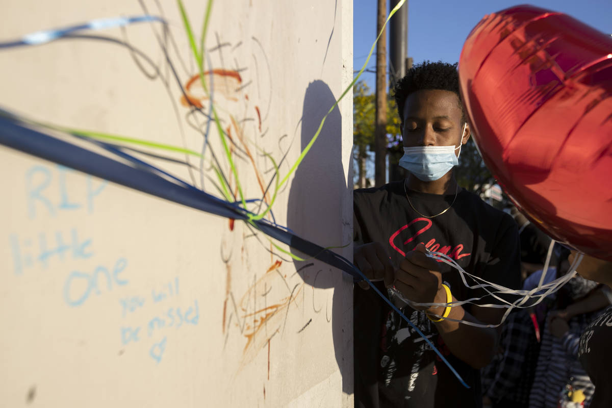 Darreon Hollis ties a ballon to a pillar during a vigil for 2-year-old Amari Nicholson outside ...