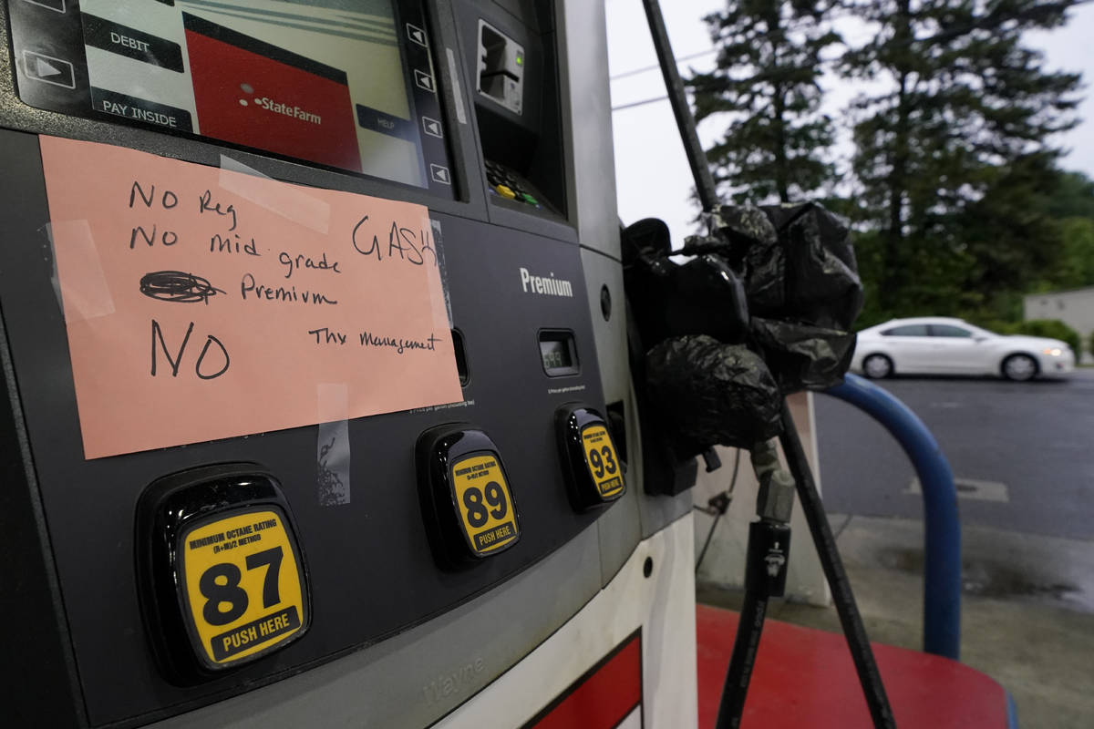 A hand written sign is posted on a gas pump, showing that the service station is out of all gra ...