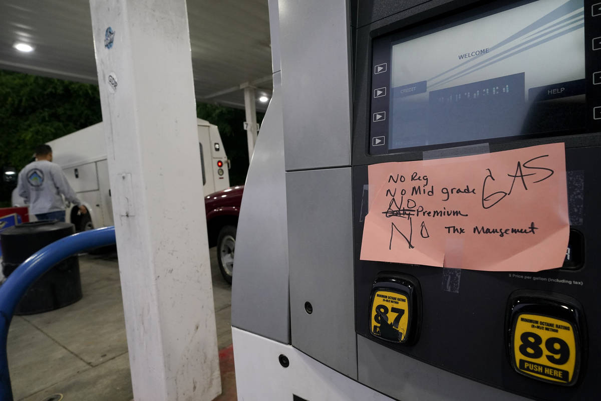 A hand written sign is posted on a gas pump, showing that the service station is out of all gra ...