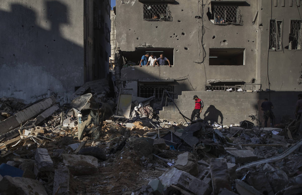 Palestinians look at destruction caused by Israeli air strikes that killed ten members of the A ...