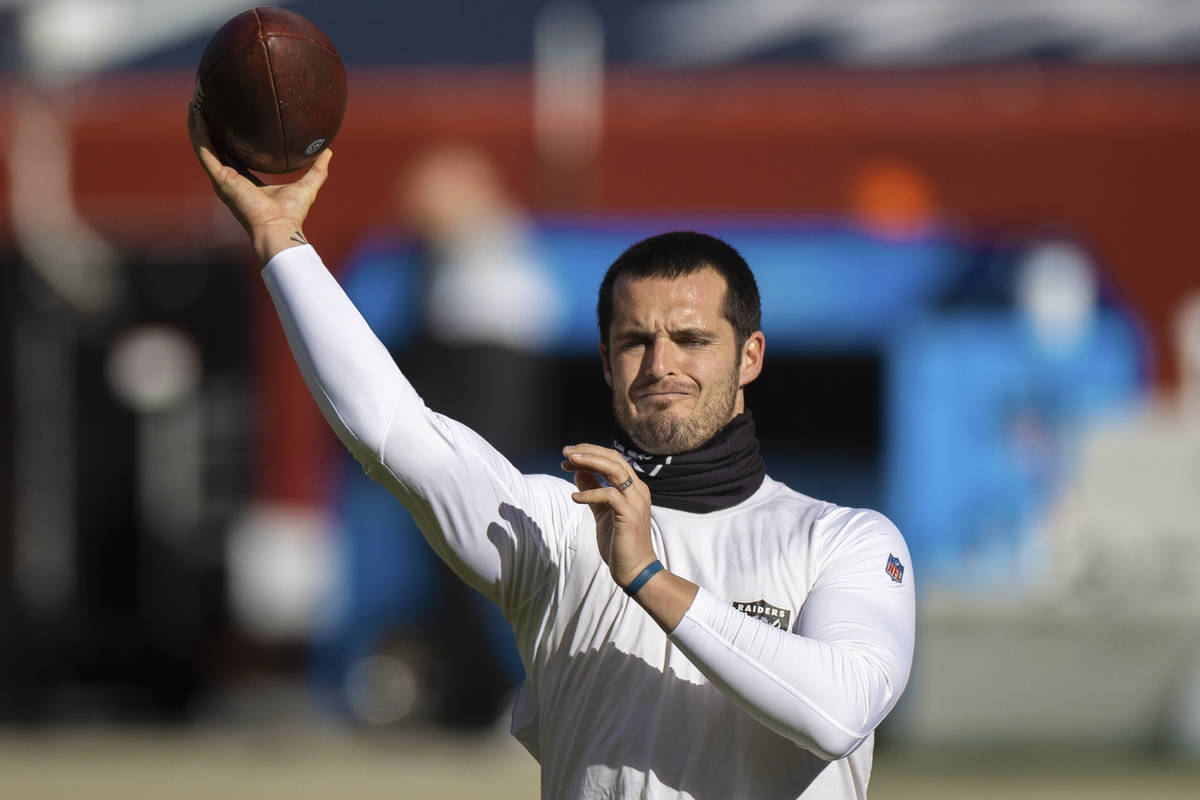 Raiders quarterback Derek Carr warms up before the start of an NFL football game against the De ...