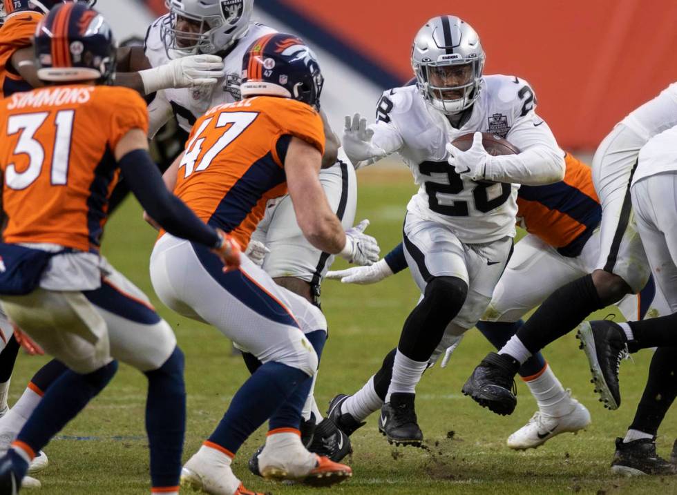 Raiders running back Josh Jacobs (28) burst through a hole past Denver Broncos inside linebacke ...