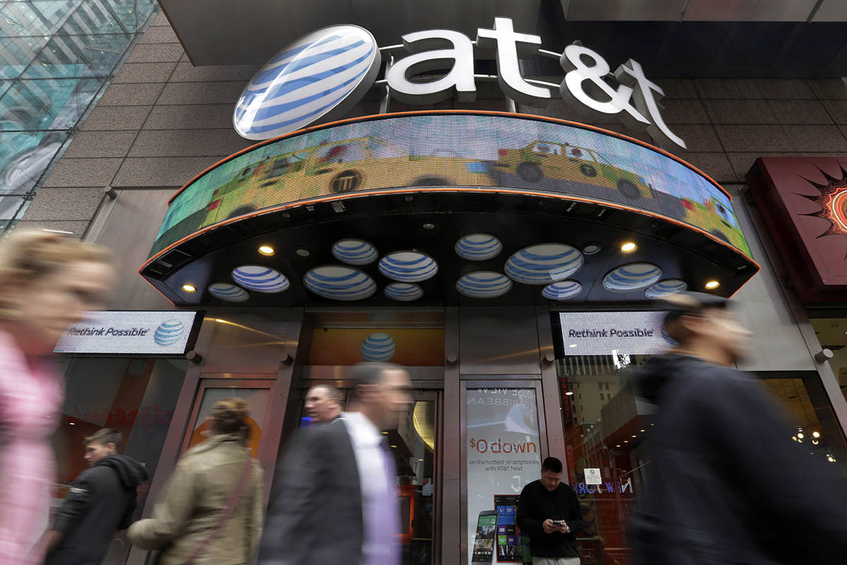 FILE - In this Oct. 21, 2014 file photo, people pass an AT&T store in New York's Times Squa ...
