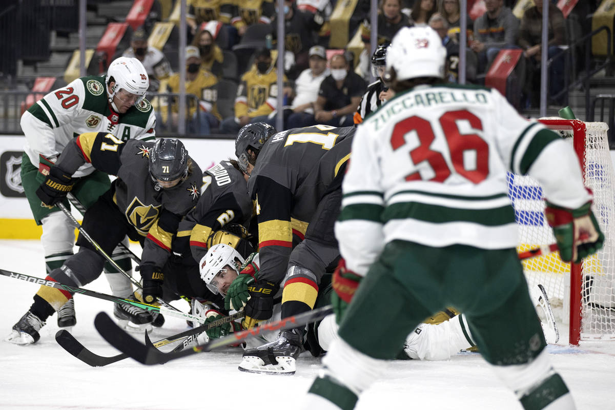 The Golden Knights and the Wild fight for the puck, including Wild center Marcus Johansson (90) ...