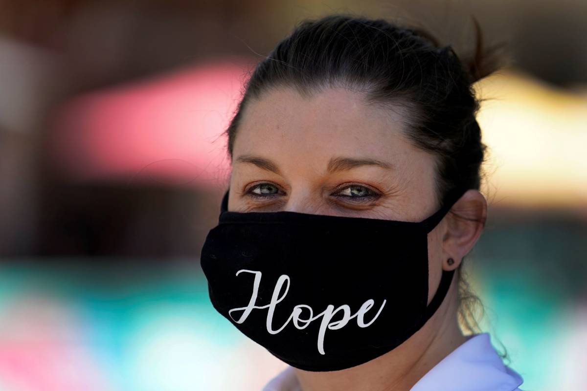 A woman wears a mask with the word "Hope" embroidered on it amid the COVID-19 pandemic Tuesday, ...