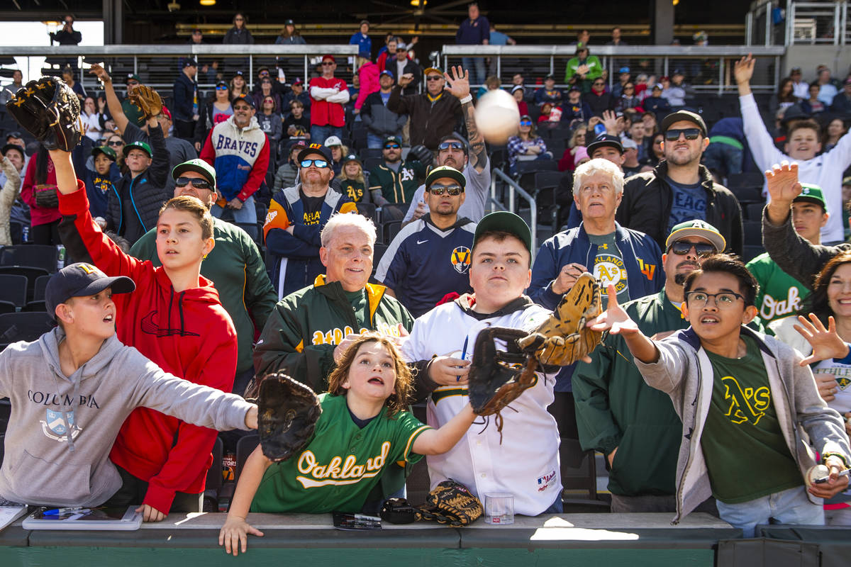 Fans work for position to catch a ball tossed by an Oakland Athletics player during a Big Leagu ...