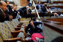 In this Jan. 6, 2021, file photo, people shelter in the House chamber as rioters try to break i ...