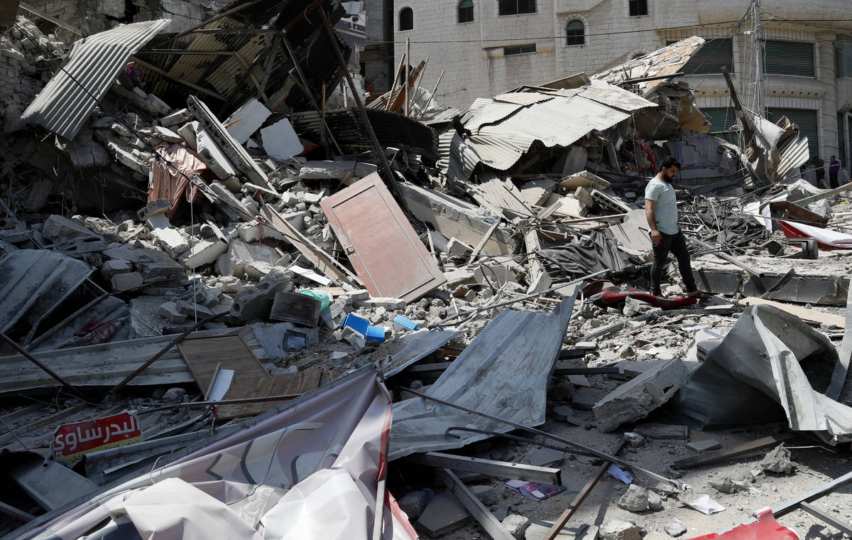 A man inspects the rubble of destroyed residential building which was hit by Israeli airstrikes ...