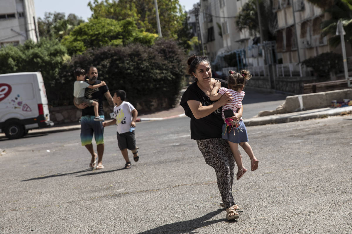 Lia Tal, 40, rushes with her children and partner to take shelter as a siren sounds a warning o ...