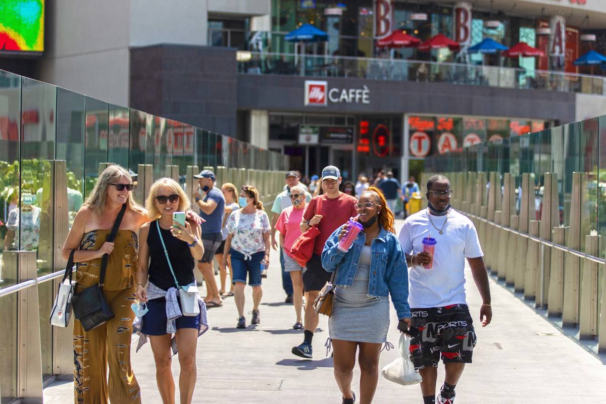 Tourists cross the pedestrian bridge connected to Harmon Corner on the Strip on Friday, April 3 ...