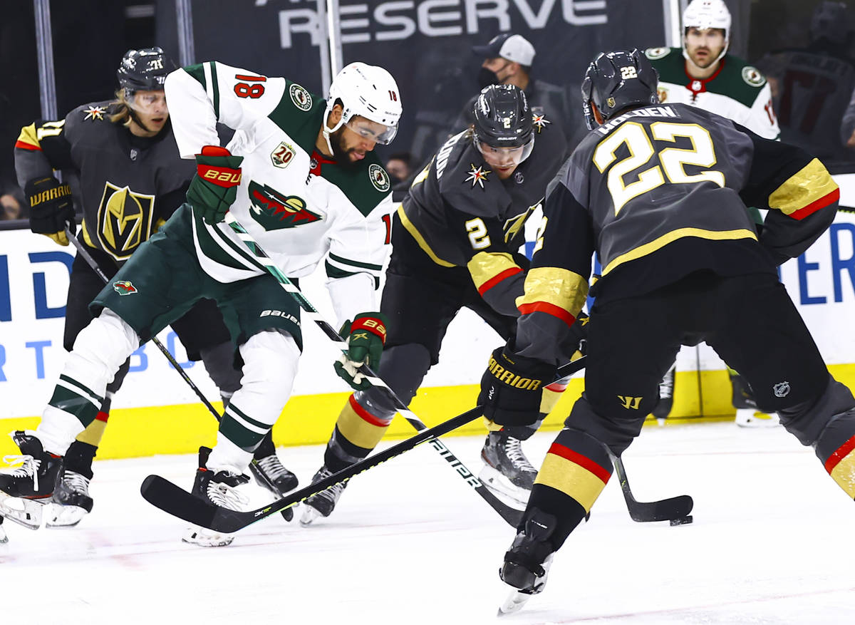 Golden Knights' defenseman Zach Whitecloud (2) skates with the puck under pressure from Minneso ...