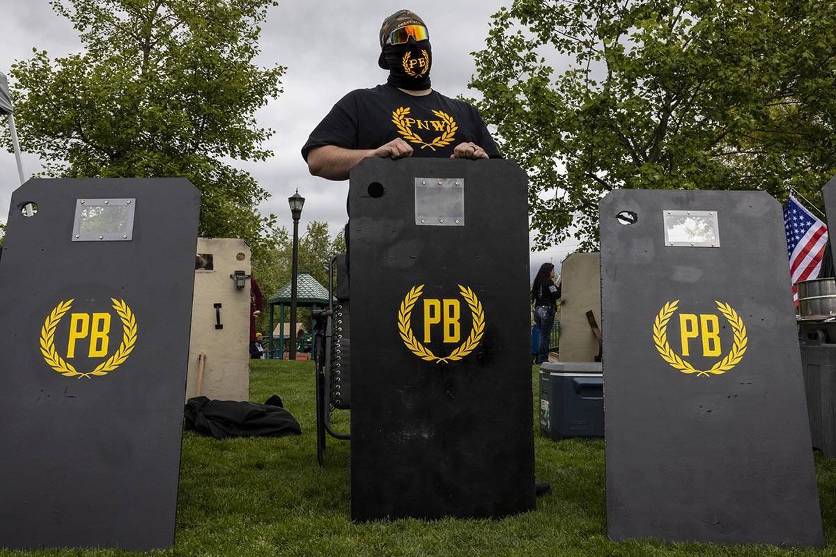 A Proud Boy supporter stands by protective shields as a few hundred people attend a second amen ...