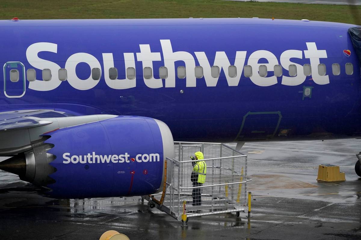 A worker uses a flashlight to inspect an engine on a Boeing 737 Max 8 built for Southwest Airli ...