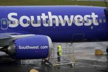 A worker uses a flashlight to inspect an engine on a Boeing 737 Max 8 built for Southwest Airli ...