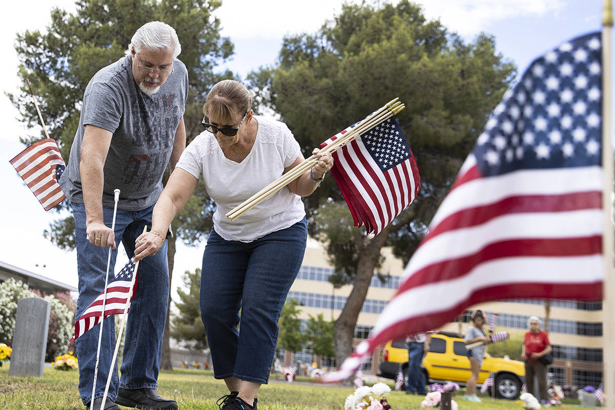 Garry Bordman and his wife Lori, both retired United States Air Force, place American flags, in ...