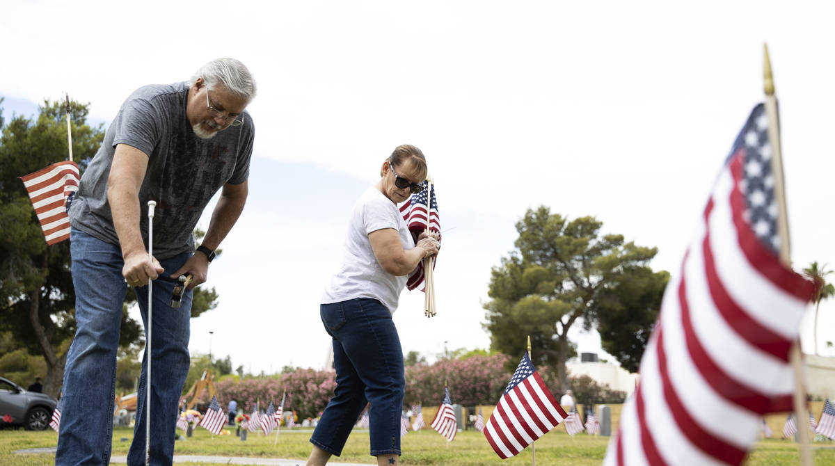 Garry Bordman and his wife Lori, both retired United States Air Force, place American flags, in ...