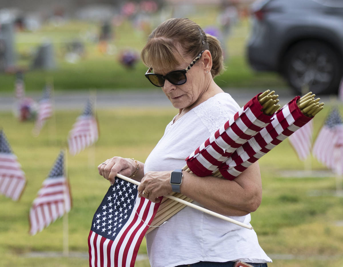 Lori Bordman, retired United States Air Force, prepares to place American flags, in honor of Me ...