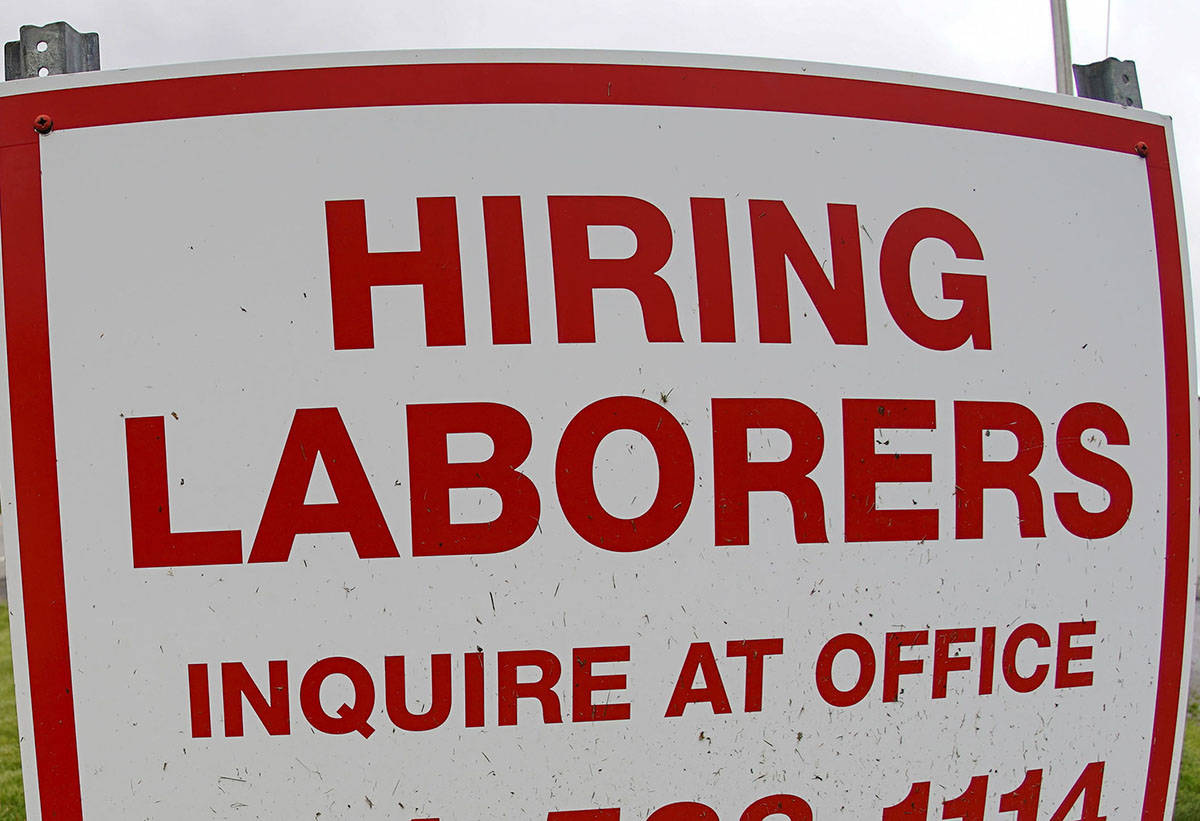In this file photo from May 5, 2021, a truck passes a sign showing a need to hire laborers outs ...