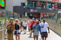 Tourists cross the pedestrian bridge connected to Harmon Corner on the Strip on Friday, April 3 ...