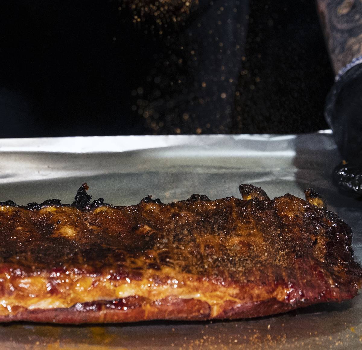 Joe Woodel, BBQ pitmaster, sprinkles seasoning on a rack of pork ribs at The Beast by Todd Eng ...