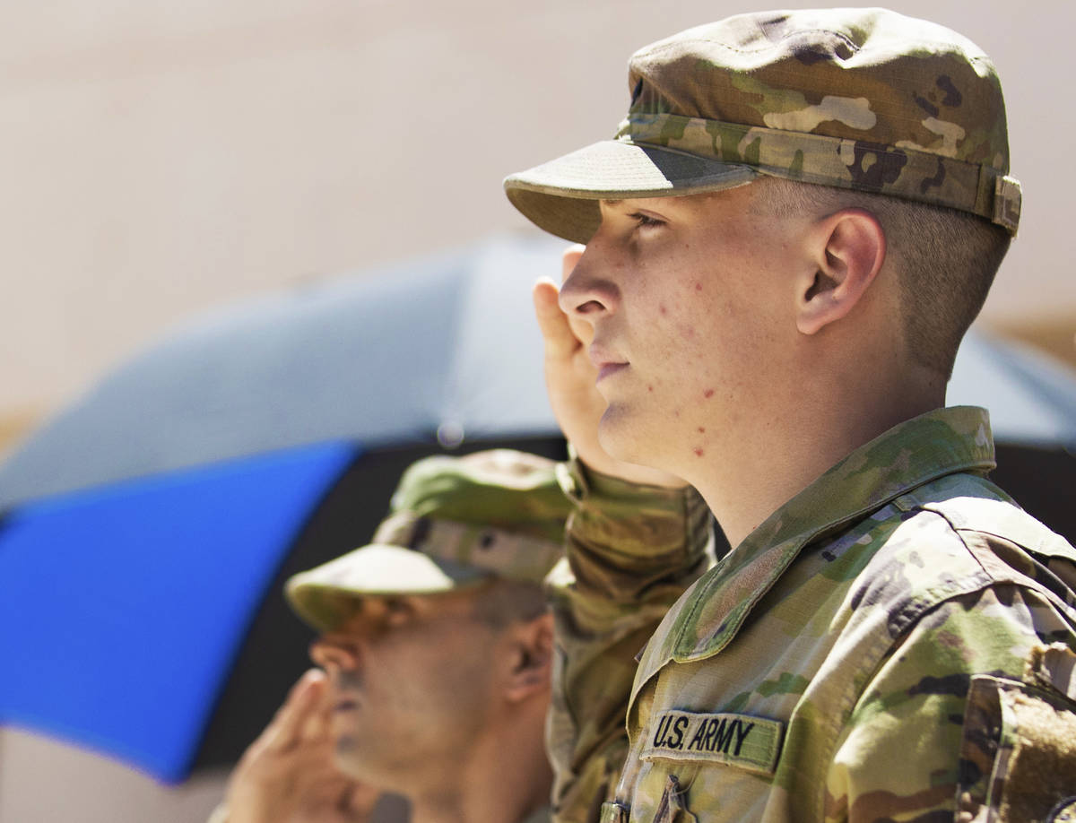 Army specialist Brendan Brown, right, and sergeant Troy Paciniharvey salute during the playing ...