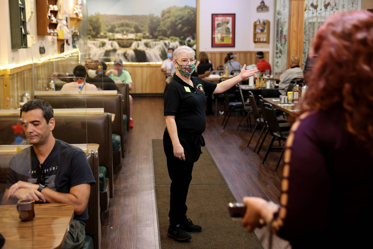 Omelet House Head Host Loni Delahuerta shows customers their table on the first day of 100 perc ...