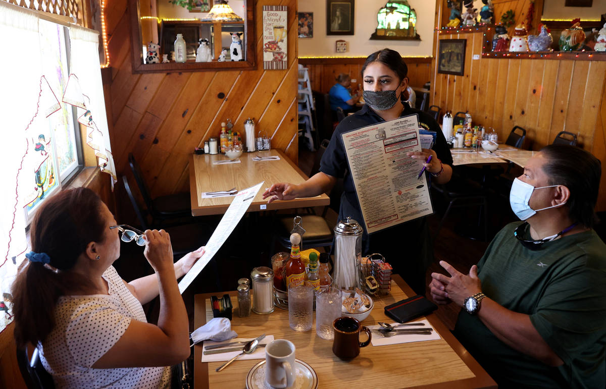 Omelet House employee Karen Guzman serves Ruth and Timothy Pineda on the first day of 100 perce ...