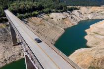 A car crosses Enterprise Bridge over Lake Oroville's dry banks Sunday, May 23, 2021, in Orovill ...