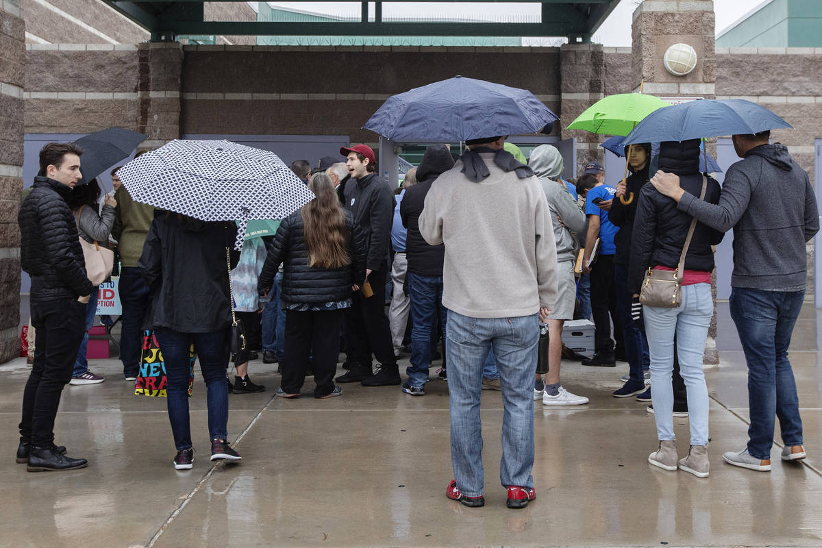 Caucusgoers and volunteers try to escape the rain before the Nevada caucus at Palo Verde High S ...