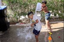Dominic Perry, 7, soaks Zair Perez, 6, while cooling off at their grandfather's house in the Be ...