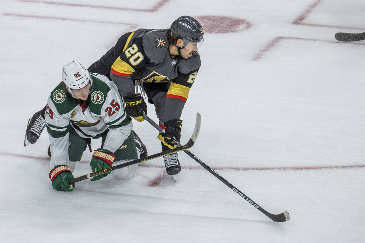 Golden Knights center Chandler Stephenson (20) eyes the puck as he tumbles over Minnesota Wild ...