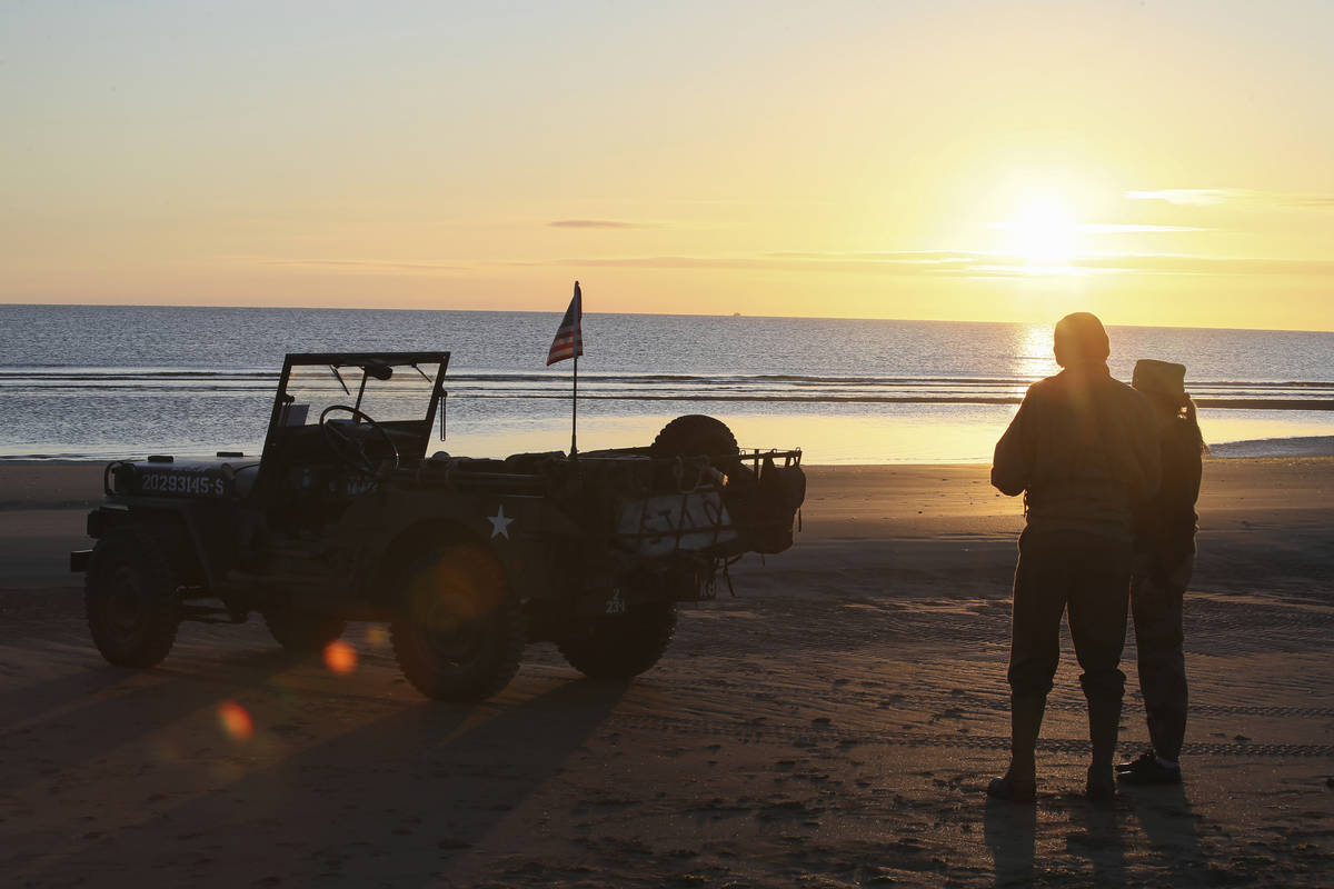 World War II reenactors gather at dawn on Omaha Beach in Saint-Laurent-sur-Mer, Normandy, Sunda ...