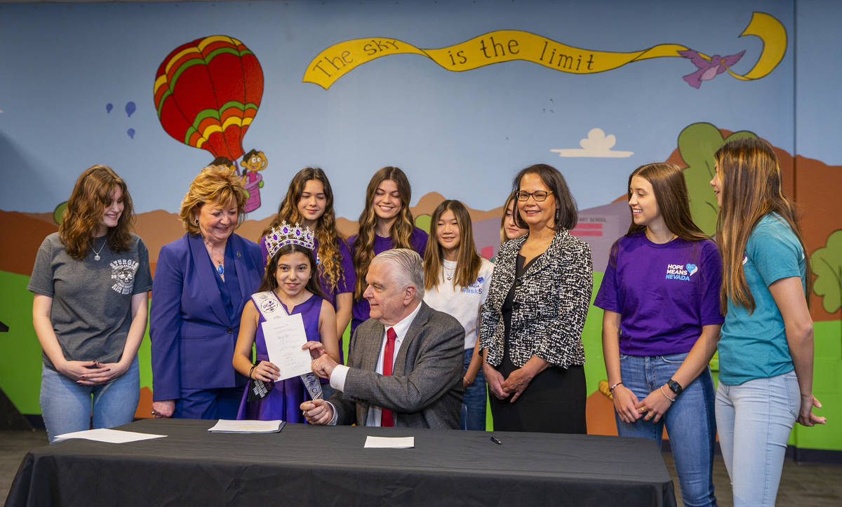 Gov. Steve Sisolak hands Miss Nevada Role Model Tayla Westerman his signed Senate Bill #249 whi ...