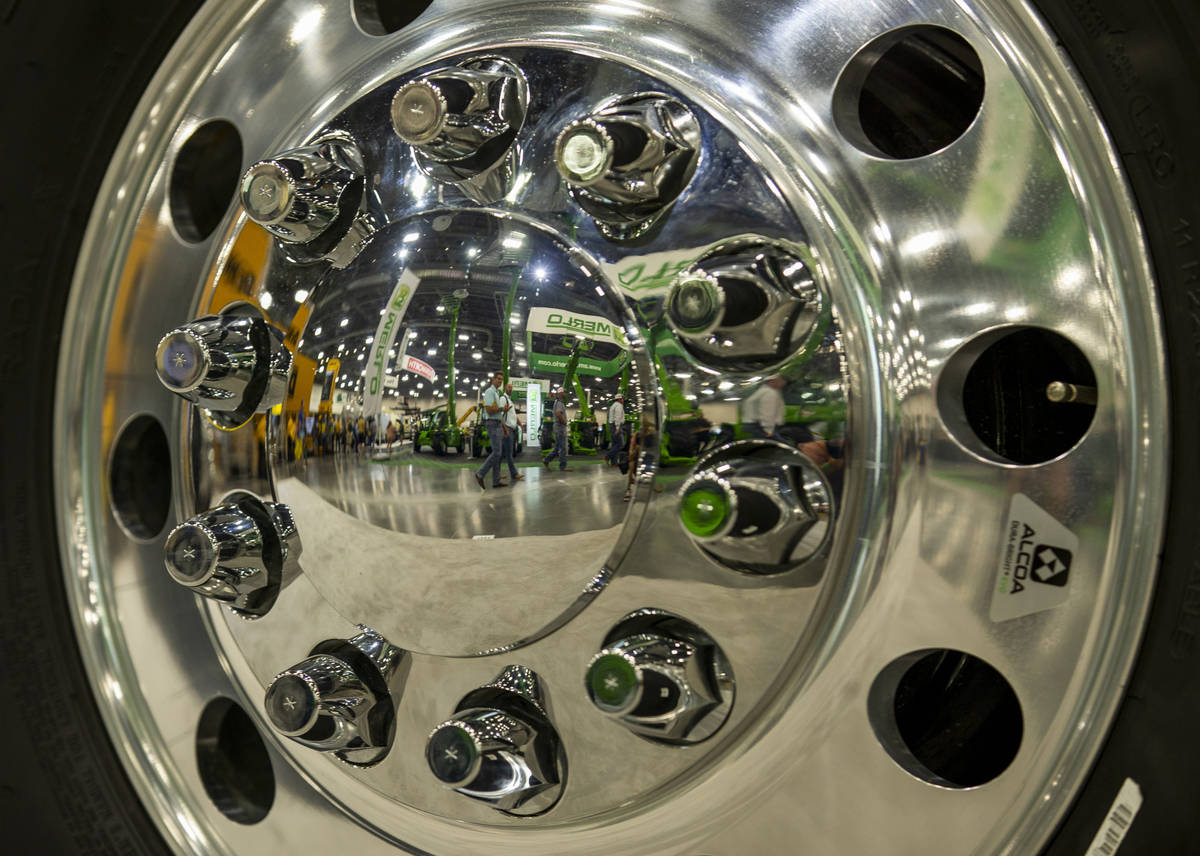 World of Concrete 2021 attendees are reflected in the rim of a Peterbilt truck on display about ...
