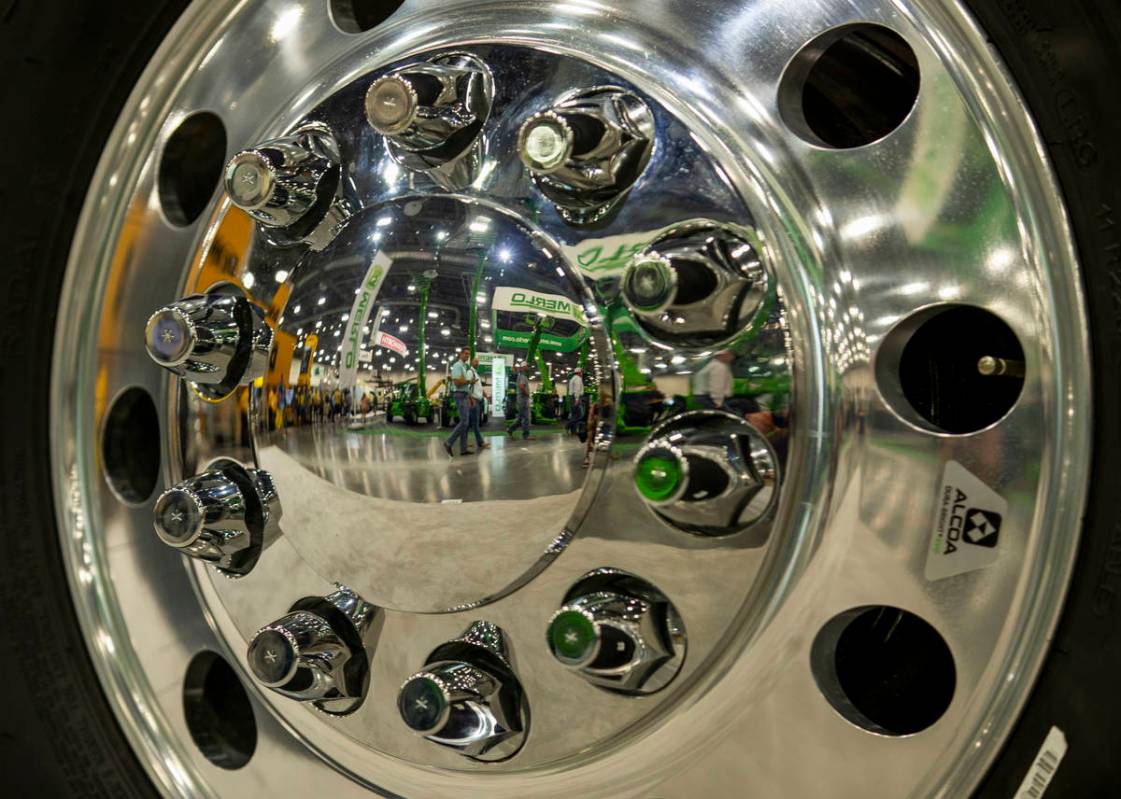 World of Concrete 2021 attendees are reflected in the rim of a Peterbilt truck on display about ...