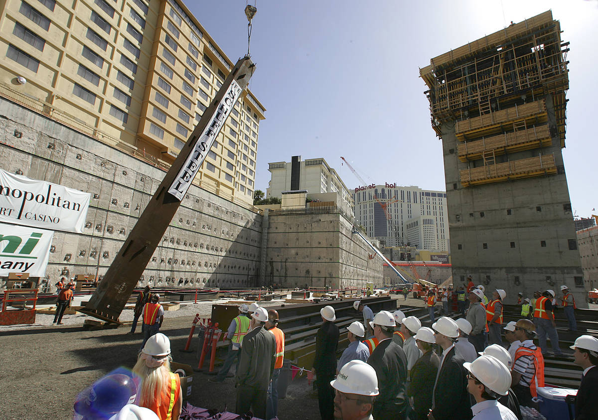 A steel column is hoisted into position as VIP guests and construction workers look on during a ...
