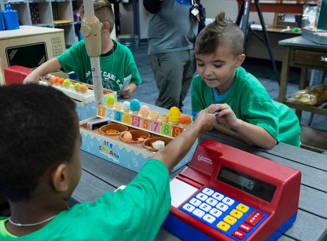 Kay Carl Elementary School student, Michael Brunetti, 6, left, collects money after selling ice ...