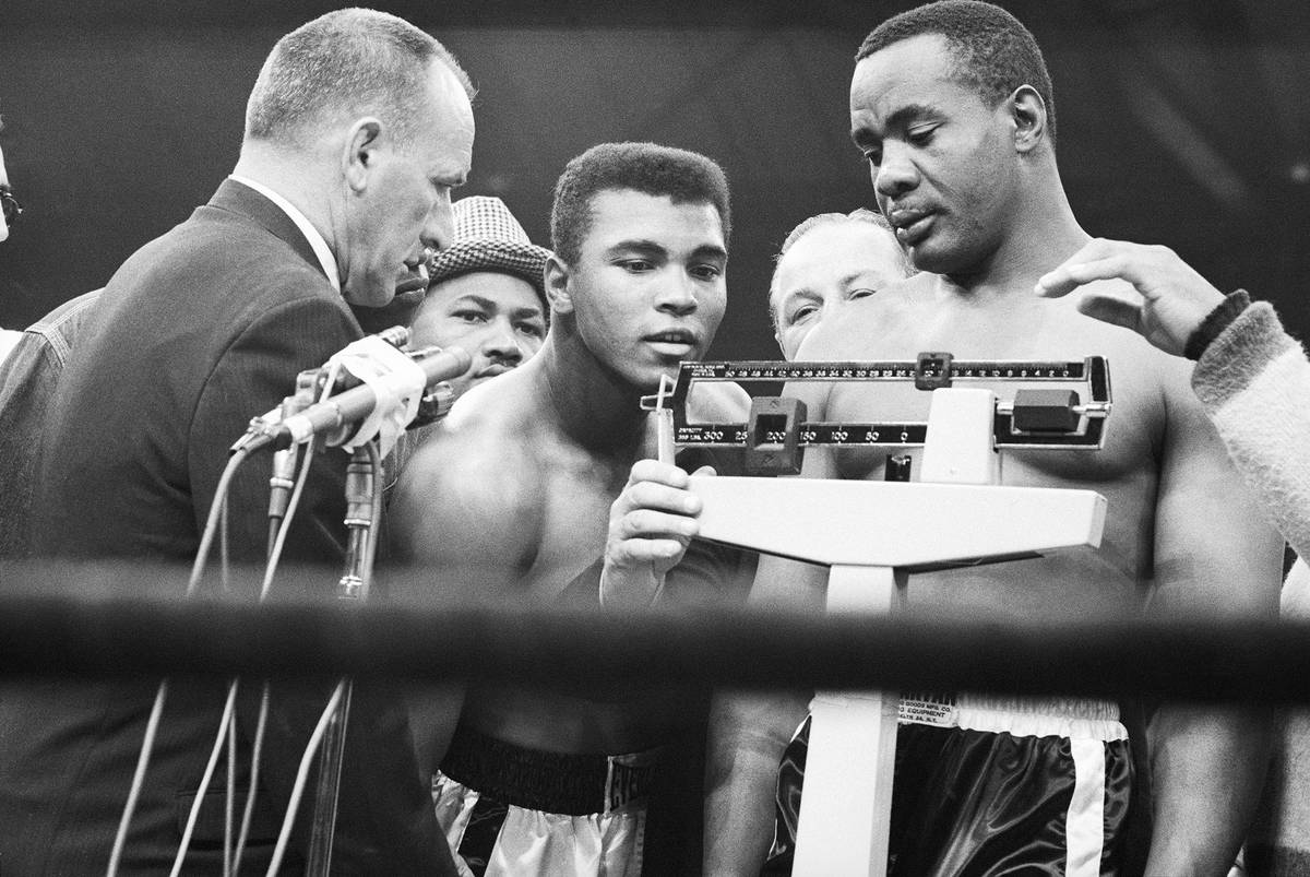 Muhammad Ali watches Sonny Liston weigh in for the rematch of the 1965 Boxing World Heavyweight ...