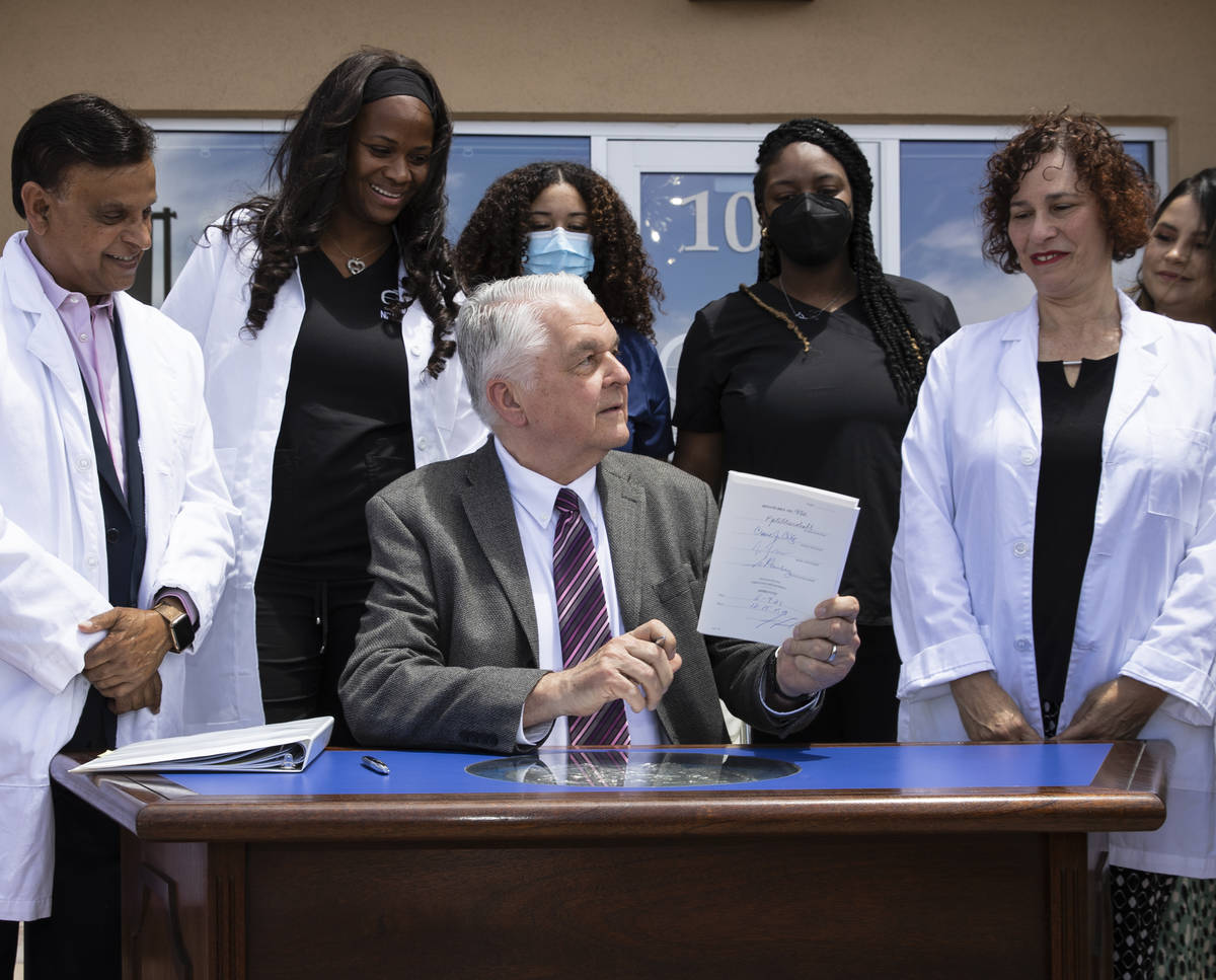 Gov. Steve Sisolak holds Senate Bill # 420, the bill that will provide a public health care opt ...