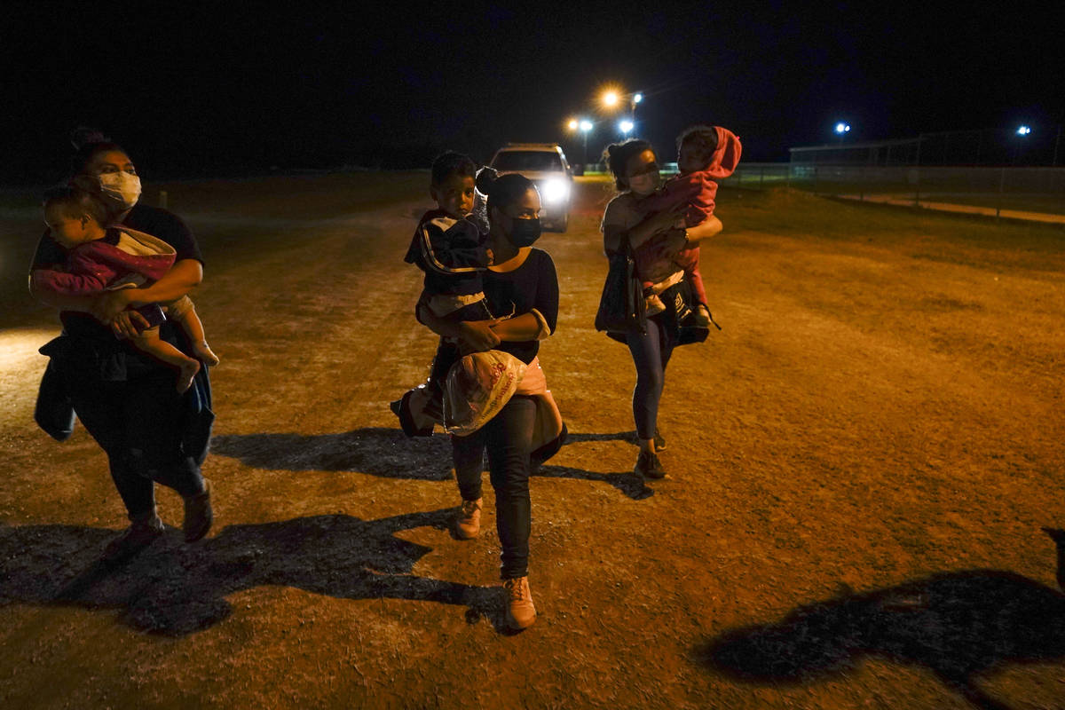 Migrant women carry children in the rain at an intake area after turning themselves in upon cro ...